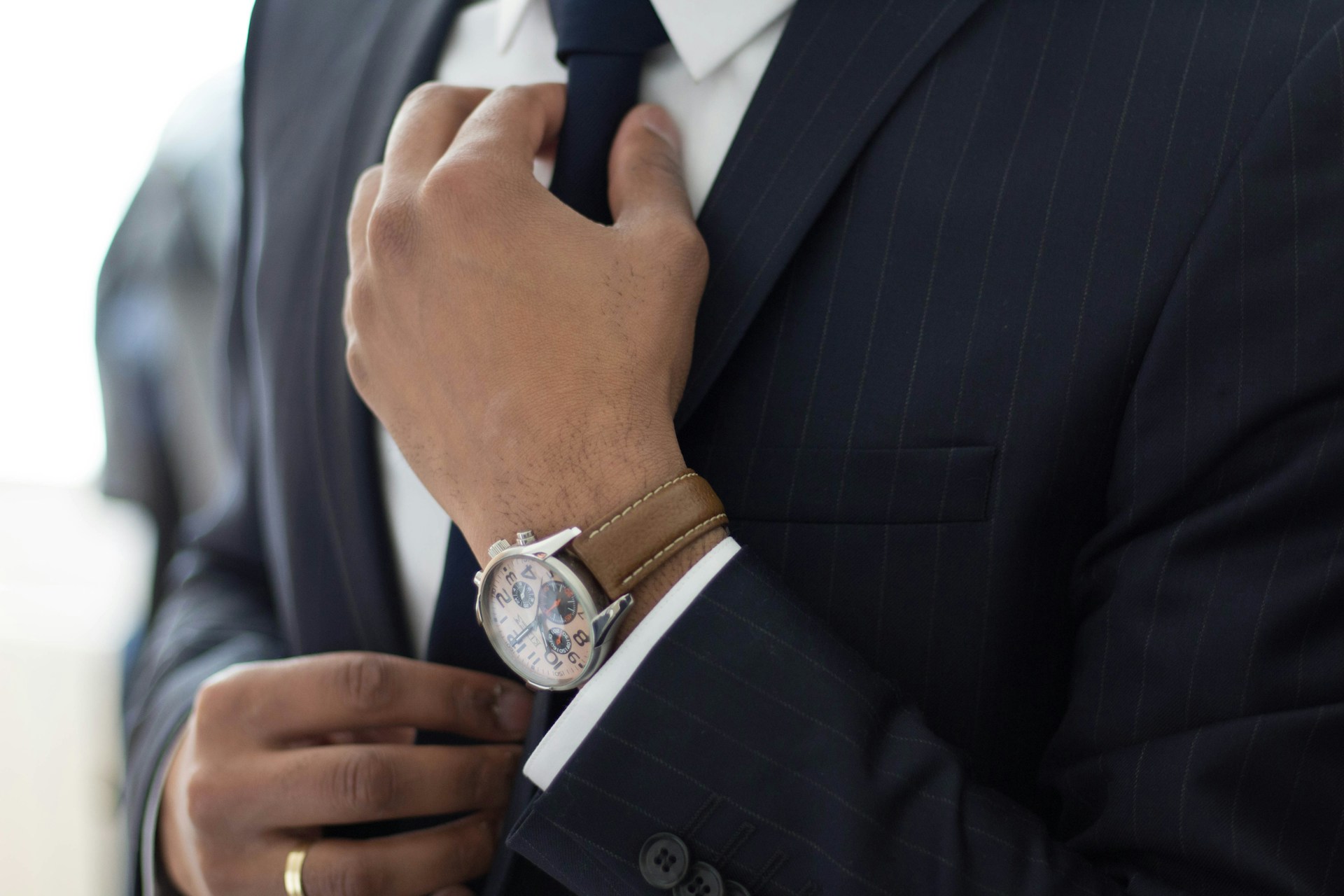 ネクタイを締めるスーツの男性の手元の画像